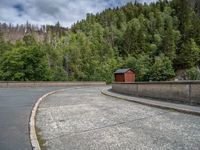 concrete walkway with trees and fenced in area on opposite sides of the road and one side of the road