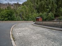 concrete walkway with trees and fenced in area on opposite sides of the road and one side of the road