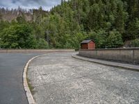 concrete walkway with trees and fenced in area on opposite sides of the road and one side of the road