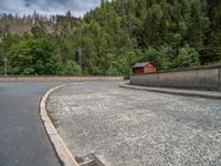 concrete walkway with trees and fenced in area on opposite sides of the road and one side of the road