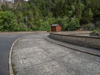 concrete walkway with trees and fenced in area on opposite sides of the road and one side of the road