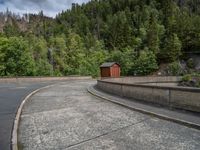 concrete walkway with trees and fenced in area on opposite sides of the road and one side of the road