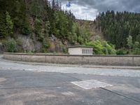 concrete walkway with trees and fenced in area on opposite sides of the road and one side of the road