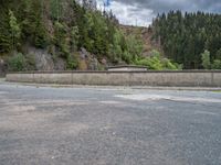 concrete walkway with trees and fenced in area on opposite sides of the road and one side of the road