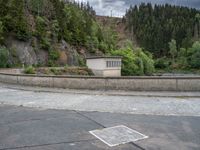 concrete walkway with trees and fenced in area on opposite sides of the road and one side of the road