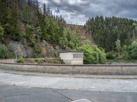 concrete walkway with trees and fenced in area on opposite sides of the road and one side of the road