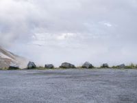 there are several large rocks and boulders standing in the middle of a field near mountains