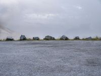 there are several large rocks and boulders standing in the middle of a field near mountains