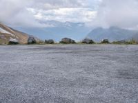 there are several large rocks and boulders standing in the middle of a field near mountains