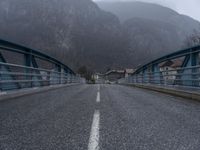 an empty street with mountains behind it and bridge in the middle of the road, with no traffic on it