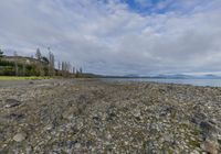 a view across a rocky beach toward the ocean with a mountain range in the distance