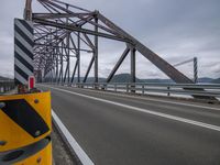 a highway bridge over the water and clouds in the sky over it are cars and traffic signs