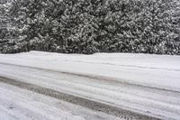 a snow covered road with trees in the distance and a truck parked on the side