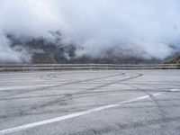 a street with some tires and a cloudy sky in the background in a mountain side parking lot