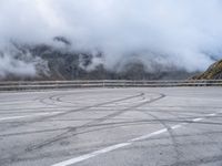 a street with some tires and a cloudy sky in the background in a mountain side parking lot