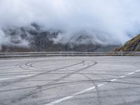 a street with some tires and a cloudy sky in the background in a mountain side parking lot