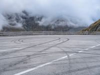 a street with some tires and a cloudy sky in the background in a mountain side parking lot