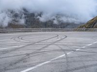 a street with some tires and a cloudy sky in the background in a mountain side parking lot