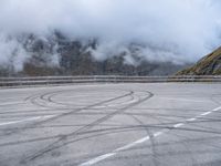 a street with some tires and a cloudy sky in the background in a mountain side parking lot