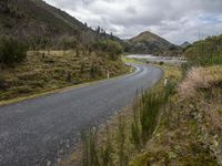 a road leading through an area with a lot of mountains in the background, and a highway is running through the field