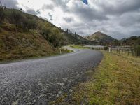 a road leading through an area with a lot of mountains in the background, and a highway is running through the field