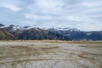 a sandy field with mountains on both sides, a few rocks and grass in the middle