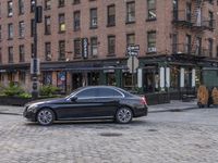 the mercedes cla sits on the side of a cobblestone street in the city