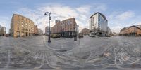 a distorted fisheye photo shows people and buildings in the distance of an outdoor square