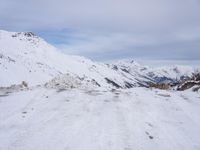 a couple snowboards is laying in the snow on a road in front of mountains