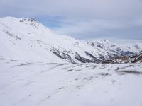 a couple snowboards is laying in the snow on a road in front of mountains