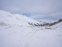 a couple snowboards is laying in the snow on a road in front of mountains