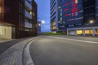 a parking garage, road and buildings at night with low lighting from the windows and street lights