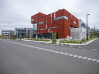 the orange building is located next to a street with an empty road underneath it, while the grey sky seems to be overcast