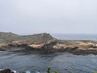 a view of the ocean on a sunny day, from the coast path of a rocky shore