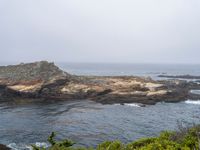 a view of the ocean on a sunny day, from the coast path of a rocky shore