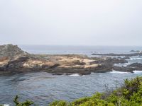 a view of the ocean on a sunny day, from the coast path of a rocky shore