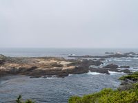 a view of the ocean on a sunny day, from the coast path of a rocky shore