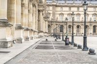 two people are sitting down on the sidewalk in front of a building in paris, france