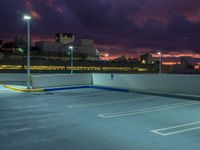 an empty parking lot at night with clouds overhead in the background and a street light out front