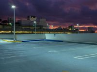 an empty parking lot at night with clouds overhead in the background and a street light out front