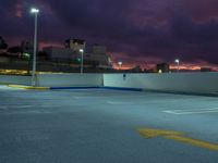 an empty parking lot at night with clouds overhead in the background and a street light out front