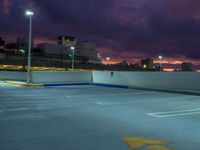 an empty parking lot at night with clouds overhead in the background and a street light out front