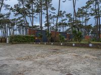 three buildings with trees and rocks behind them and in the foreground, there is a bench