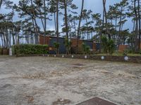 three buildings with trees and rocks behind them and in the foreground, there is a bench