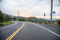 a curve in the road with a street sign on it's side and mountain area on the other side