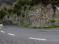 a steep slope of rock with a sign on it in the middle of the road