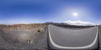 the view from an upside down shot of a road with some rocky hills and mountains in the background