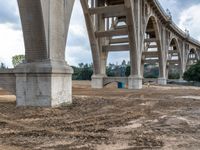 a construction site near an arch with a bridge crossing it and the building in the distance