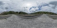 the view from inside a fisheye lens of a road with mountains in the background