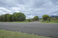 an empty road, grass and dirt field on a cloudy day with an arrow pointing up at the road